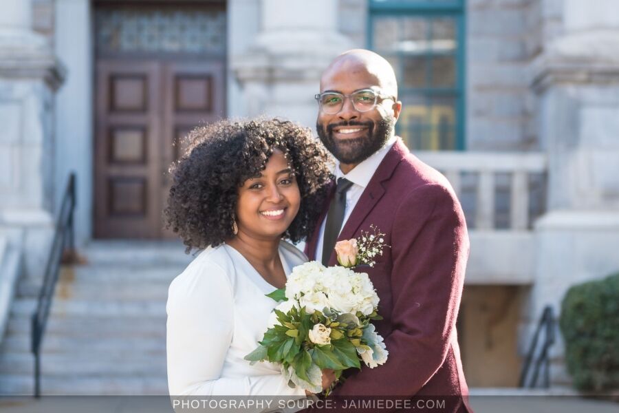 Newlyweds smiling in front of a historic courthouse entrance after their elopement