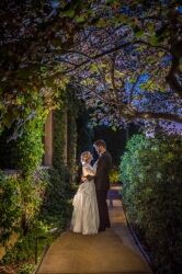 Bride and groom embracing on a lit garden path at night