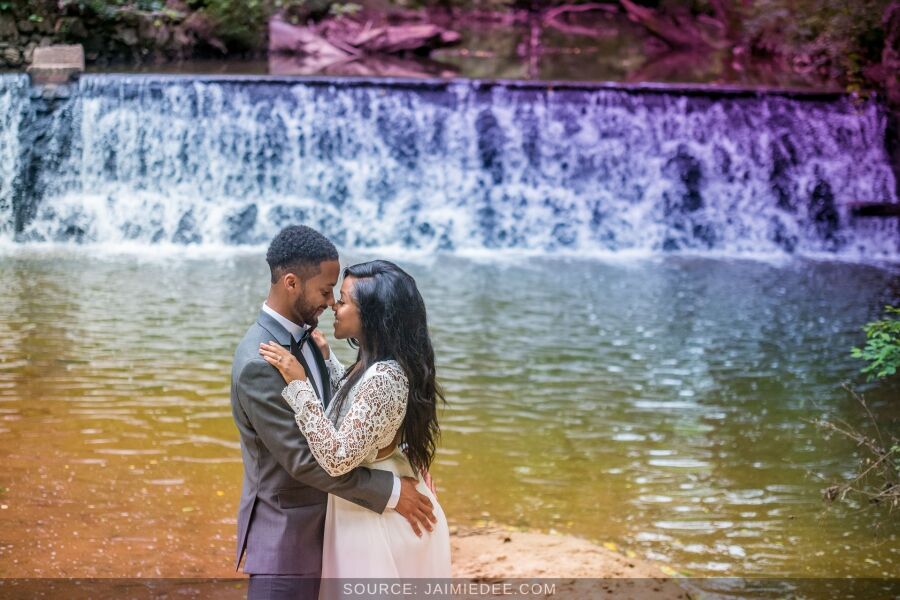 Bride and groom standing in front of the waterfall wall at Lullwater Park in Atlanta